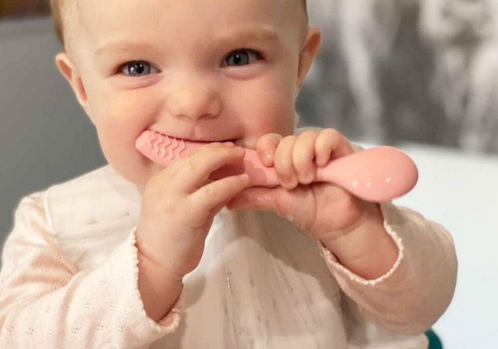 teething baby chewing silicone spoon teether smiling