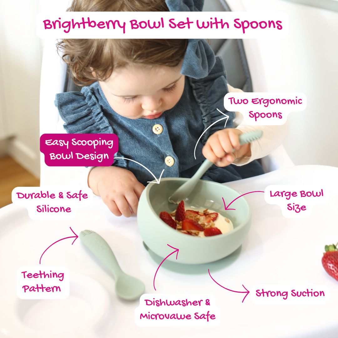 Toddler using the Brightberry Bowl Set with Spoons in sage green. The bowl features an easy-scooping design, large size, strong suction base, and is made from durable & safe LFGB platinum silicone. Includes two ergonomic spoons with a teething pattern. Dishwasher and microwave safe, ideal for self-feeding.