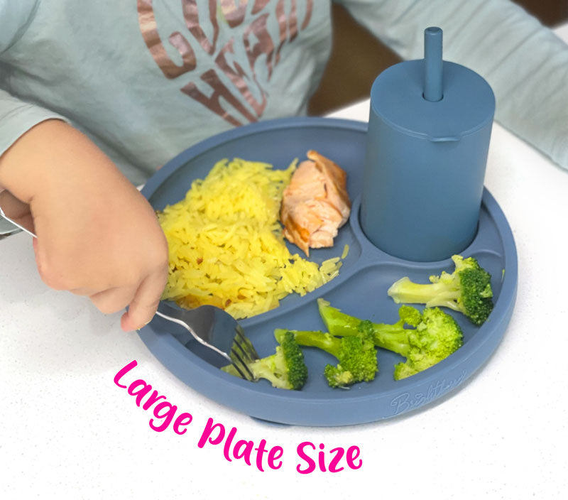 girl eating dinner from silicone suction plate with child utensils 